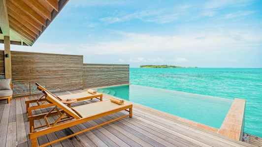 Terassi, jossa on kaksi aurinkotuolia, infinity-allas ja näkymä turkoosille merelle. (Tekoälyn luoma teksti)
