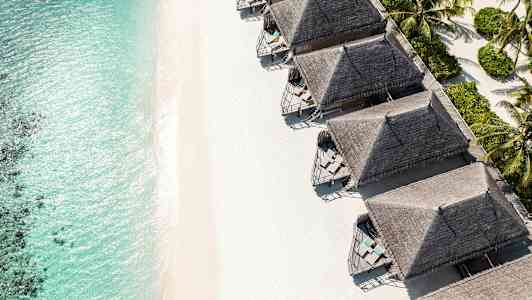 Ranta turkoosilla vedellä ja useita rantabungaloweja. (Tekoälyn luoma teksti)