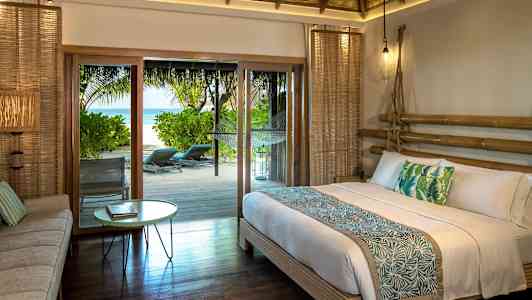 Makuuhuone, jossa on parisänky ja trooppinen sisustus, sekä uloskäynti terassille, josta on merinäköala. (Tekoälyn luoma teksti)