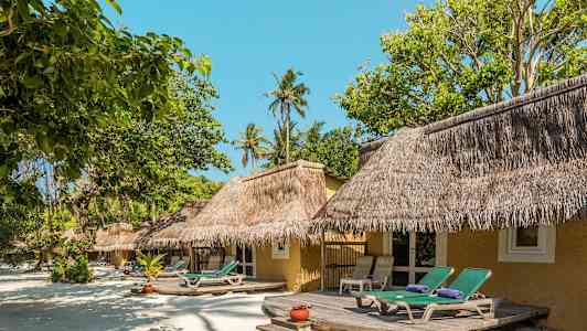 Rantabungalow olkikatolla ja aurinkotuoleilla, ympärillä vehreää kasvillisuutta. (Tekoälyn luoma teksti)