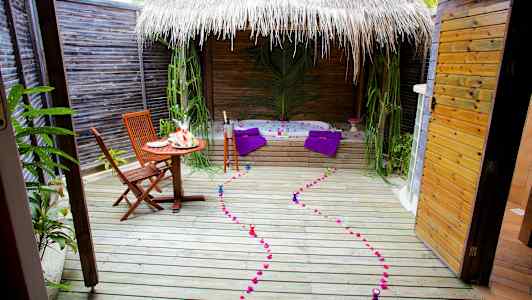 Ulkoilmaterassi, jossa on pöytä, tuolit, poreallas ja koristeita. (Tekoälyn luoma teksti)