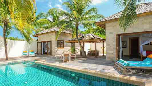 Villa yksityisellä uima-altaalla, ympärillä aurinkotuoleja ja trooppisia palmuja. (Tekoälyn luoma teksti)