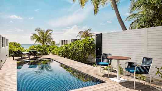 Yksityinen uima-allas terassilla, jossa aurinkotuoleja ja merinäköala. (Tekoälyn luoma teksti)