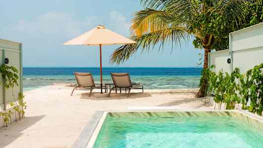 Aurinkotuolit varjon alla rannalla ja meren äärellä. (Tekoälyn luoma teksti)