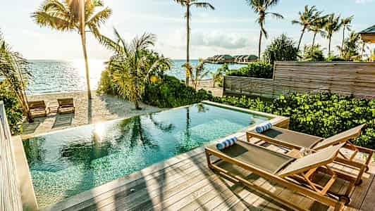 Uima-allas aurinkotuoleilla terassilla hiekkarannan ja meren äärellä. (Tekoälyn luoma teksti)