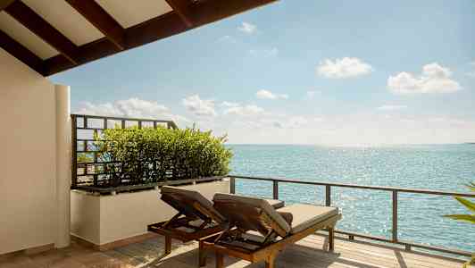 Kaksi aurinkotuolia terassilla, josta on näkymä merelle. (Tekoälyn luoma teksti)