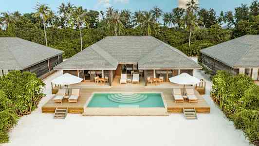 Huvilat yksityisine uima-altaineen ja aurinkoterasseineen vehreyden keskellä valkoisen hiekkarannan äärellä. (Tekoälyn luoma teksti)