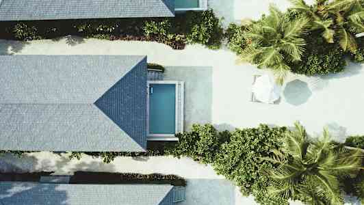 Ilmakuva lomamökeistä, joissa pieniä uima-altaita ja kasvillisuutta. (Tekoälyn luoma teksti)