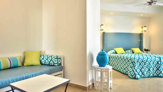 Hotellihuone, jossa on vuode, vaaleat sisustuselementit ja koristeellisia tyynyjä. (Tekoälyn luoma teksti)