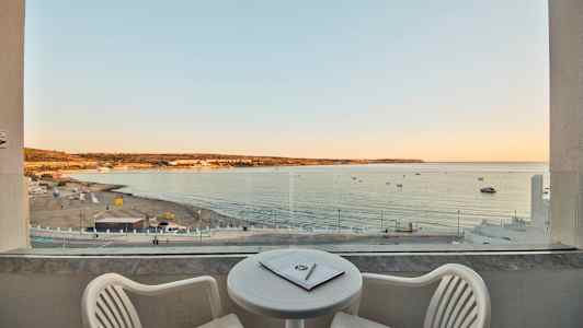 Näkymä parvekkeelta hiekkarannalle ja merelle auringonlaskun aikaan. (Tekoälyn luoma teksti)