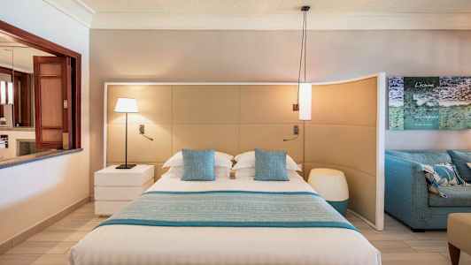 Moderni makuuhuone, jossa on suuri sänky, sinisiä koristeellisia tyynyjä ja yhteensopivia vuodevaatteita. (Tekoälyn luoma teksti)