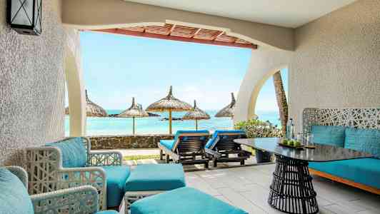 Terassi, jossa sinisiä istuimia ja näkymä merelle aurinkovarjojen kanssa. (Tekoälyn luoma teksti)