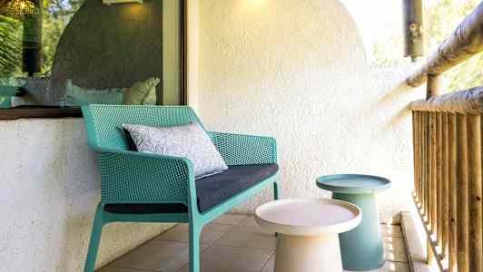 Terassi, jolla vihreä tuoli ja pieniä pöytiä. (Tekoälyn luoma teksti)