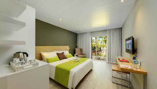 Hotellihuone, jossa parivuode, kirjoituspöytä ja parveke, jolta näkymä puihin ja vehreyteen. (Tekoälyn luoma teksti)