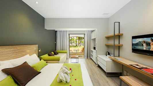 Moderni hotellihuone, jossa on sänky, työpöytä, sohva ja näkymä puutarhaan. (Tekoälyn luoma teksti)