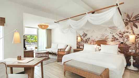 Valoisa makuuhuone ja olohuone, jossa sänkyjä, istuimia ja trooppisia koristeita. (Tekoälyn luoma teksti)