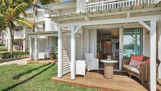 Terassi, jossa istuinkalusteita valkoisen rakennuksen ja nurmikon vieressä. (Tekoälyn luoma teksti)