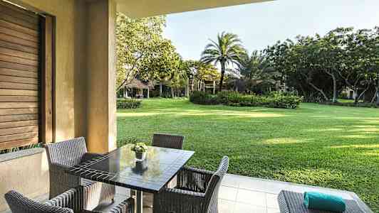 Ulkoalue, jossa pöytä ja tuolit, näkymä vehreään puutarhaan. (Tekoälyn luoma teksti)