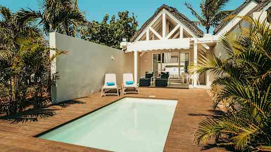 Villa, jossa on uima-allas, aurinkotuoleja ja vihreä ympäristö. (Tekoälyn luoma teksti)