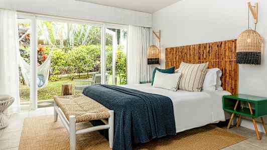 Makuuhuone, jossa on parivuode, puuyksityiskohtia ja suuret ikkunat näkymällä vihreään. (Tekoälyn luoma teksti)