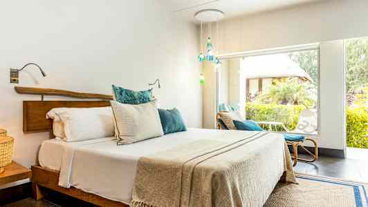 Valoisa makuuhuone, jossa on parivuode ja suuret ikkunat vehreään puutarhaan. (Tekoälyn luoma teksti)