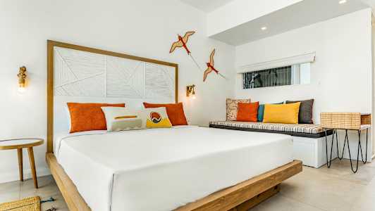 Moderni hotellihuone, jossa parivuode ja värikkäitä tyynyjä. (Tekoälyn luoma teksti)