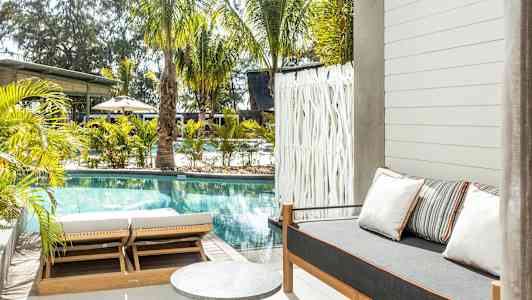 Ulkotila, jossa uima-allas, aurinkotuoleja ja sohva tyynyineen. (Tekoälyn luoma teksti)