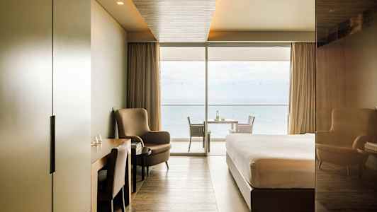 Moderni hotellihuone, josta on merinäköala suurten ikkunoiden läpi. (Tekoälyn luoma teksti)