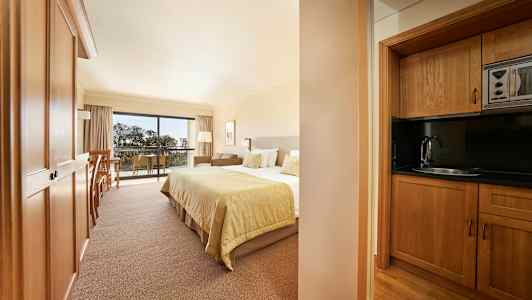 Kuva hotellihuoneesta, jossa on sänky ja puinen keittiö. (Tekoälyn luoma teksti)