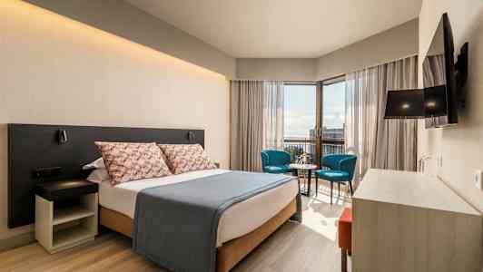 Moderni hotellihuone, jossa parivuode, oleskelutila ja näkymä. (Tekoälyn luoma teksti)