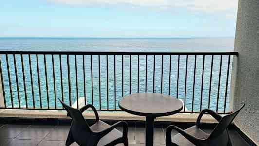 Kaksi tuolia ja pöytä parvekkeella merinäköalalla. (Tekoälyn luoma teksti)