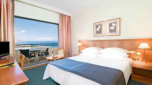 Hotellihuone, jossa parivuode, yöpöytä ja parveke merinäköalalla. (Tekoälyn luoma teksti)