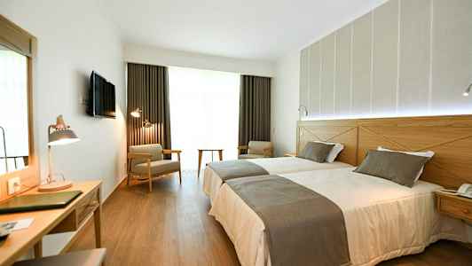 Hotellihuone, jossa kaksi erillistä vuodetta, kirjoituspöytä ja istumapaikkoja. (Tekoälyn luoma teksti)