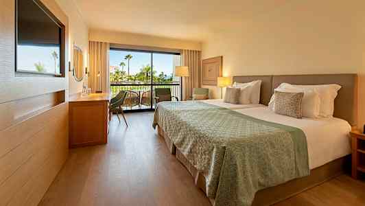 Moderni hotellihuone, jossa parisänky ja taustalla parveke. (Tekoälyn luoma teksti)