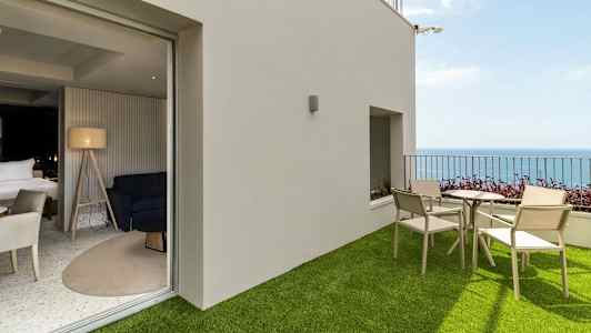 Terassi, jossa tekonurmi, pöytä ja tuolit sekä merinäköala, yhdistetty moderniin huoneeseen sisustuksella. (Tekoälyn luoma teksti)