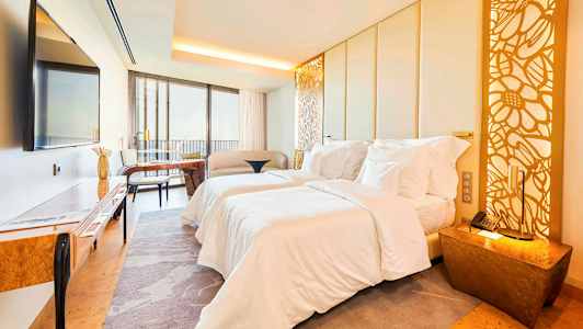 Kuva nykyaikaisesta hotellihuoneesta, jossa on kaksi sänkyä, istuinryhmä, huonekalut ja koristeellinen valaistus. (Tekoälyn luoma teksti)