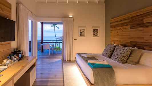 Hotellihuone, jossa on suuri sänky ja pääsy terassille ja näkymä merelle. (Tekoälyn luoma teksti)