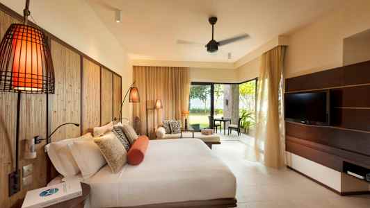 Hotellihuone, jossa on suuri sänky, sohva ja televisio sekä näköala vehreään puutarhaan. (Tekoälyn luoma teksti)