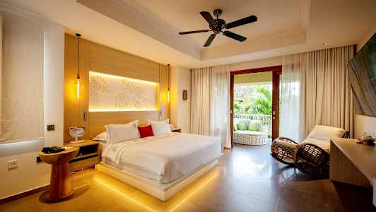 Moderni makuuhuone, jossa suuri sänky, istumapaikkoja ja avoin parveke, josta näkymä vehreyteen. (Tekoälyn luoma teksti)