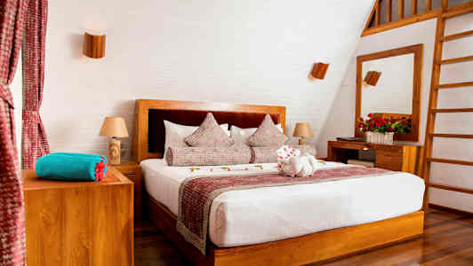 Tyylikäs makuuhuone, jossa on parivuode, puuelementtejä ja koristellut tyynyt. (Tekoälyn luoma teksti)