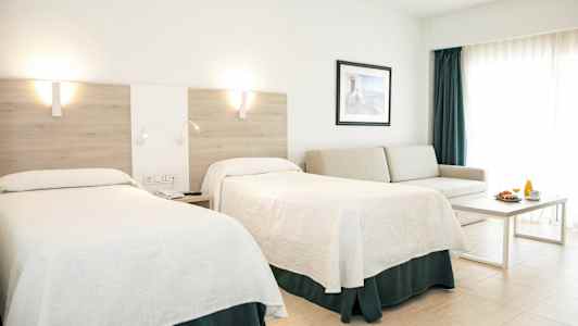 Hotellihuone, jossa on kaksi sänkyä, sohva, pöytä ja aamiaistarjoilu. (Tekoälyn luoma teksti)