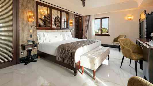 Hotellihuone, jossa suuri sänky, istuimet ja työpöytä. (Tekoälyn luoma teksti)