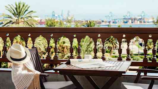 Parveke, jossa pöytä ja tuoleja, näkymä puihin ja teollisuusalueelle kaukaisuudessa. (Tekoälyn luoma teksti)