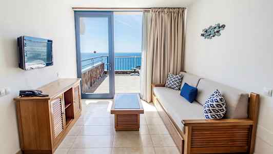 Hotellihuone, jossa oleskelutila ja näköala merelle parvekkeelta. (Tekoälyn luoma teksti)