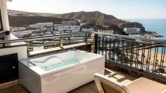 Terassi poreammeella ja näkymä lahden yli, jossa hotelleja ja ranta. (Tekoälyn luoma teksti)