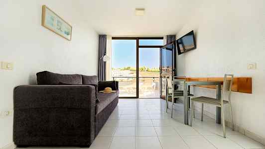 Olohuone, jossa on tumma sohva, ruokapöytä tuoleineen ja parveke, josta on näkymä. (Tekoälyn luoma teksti)