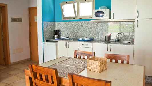 Keittiö, jossa pöytä ja neljä puutuolia. (Tekoälyn luoma teksti)