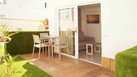 Terassi, jossa pöytä ja tuolit, oven edessä, joka johtaa huoneeseen, jossa on sohva. (Tekoälyn luoma teksti)