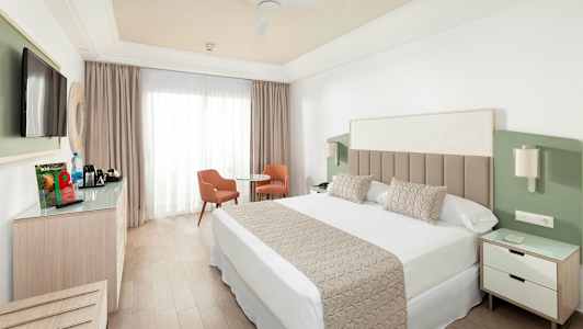 Hotellihuone, jossa parisänky, televisio, istuinryhmä ja vaatekaappi. (Tekoälyn luoma teksti)