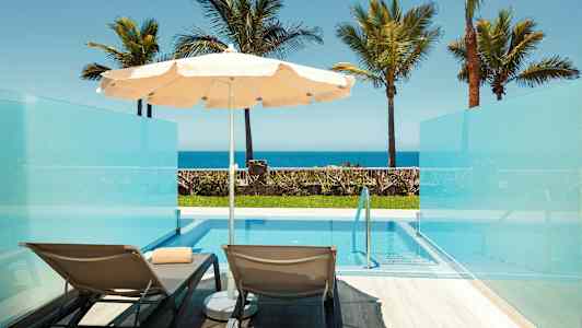 Kuva kahdesta aurinkotuolista ja aurinkovarjosta yksityisellä uima-altaalla, meren näkymä. (Tekoälyn luoma teksti)